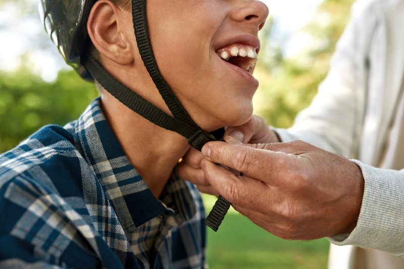 Boy smiling as father fits his helmet